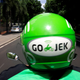 The back of a green helmet is show on a person that is riding a scooter.